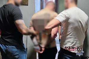 Na zdjęciu policjanci prowadzą zatrzymanego mężczyznę.