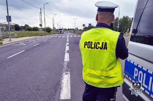 Na zdjeciu policjant oraz radiowóz.