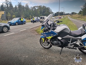 Na zdjęciu policyjny motocykl oraz policjanci podczas kontroli stanu trzeźwości.