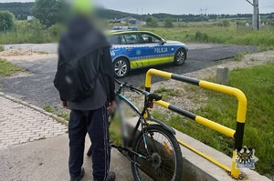 Na zdjęciu rowerzysta przy rowerze oraz radiowóz.