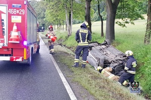 Na zdjęciu strażacy oraz samochód, który dachował w rowie.
