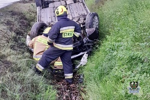Na zdjęciu strażacy oraz samochód, który dachował w rowie.