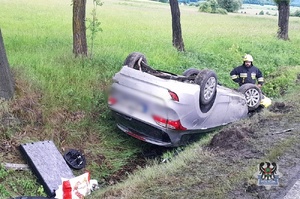 Na zdjęciu strażacy oraz samochód, który dachował w rowie.