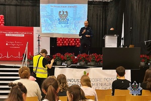 Na zdjęciu policjant prowadzi pogadankę z uczestnikami spotkania.