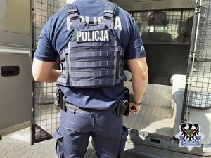 Policjant przy busie policyjny przeznaczonym do przewożenia  osób do osadzenia