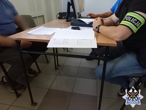 policjant podczas przesłuchania zatrzymanego