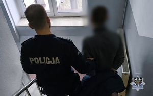 Na zdjęciu policjant prowadzi zatrzymanego poszukiwanego.