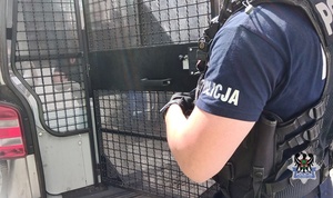 Na zdjęciu policjant otwiera drzwi radiowozu.