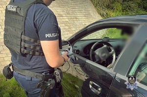 Na zdjęciu policjant sprawdza stan trzeźwości kierujacego.
