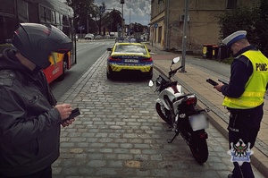 Na zdjęciu radiowóz oraz policjanci podczas kontroli drogowej.