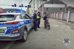 Na zdjęciu radiowóz oraz policjanci podczas kontroli drogowej.