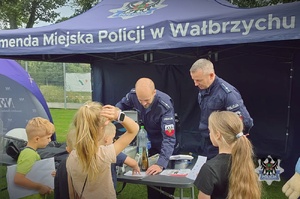 Na zdjęciu policjant oraz uczestnicy festynu.