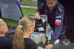 Na zdjęciu policjant oraz uczestnicy festynu.