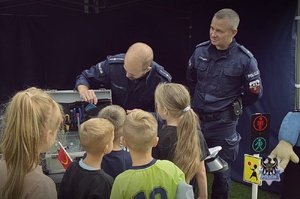 Na zdjęciu policjant oraz uczestnicy festynu.