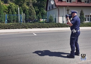 Na zdjęciu policjant w trakcie ręcznego pomiaru prędkości.