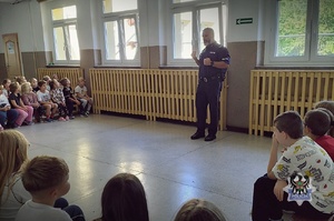 Na zdjęciu policjant podczas spotkanie z uczniami szkoły podstawowej.