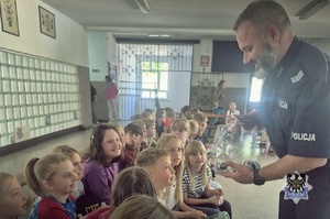 Na zdjęciu policjant podczas spotkanie z uczniami szkoły podstawowej.