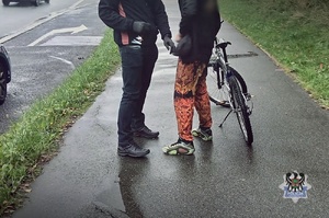 Na zdjęciu policjant kontroluje rowerzystę.