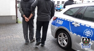 policjanci prowadzą zatrzymanego do radiowozu