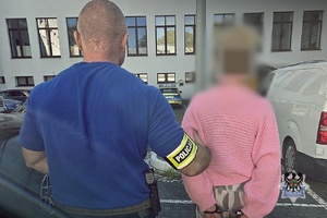 Na zdjęciu policjant prowadzi zatrzymaną kobietę.