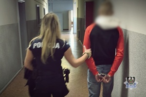 Na zdjęciu policjantka prowadzi zatrzymanego mężczyznę.