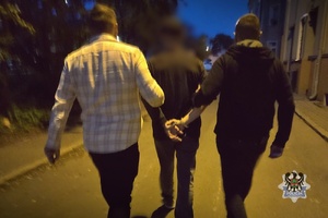 Na zdjęciu policjanci prowadzą zatrzymanego mężczyznę.