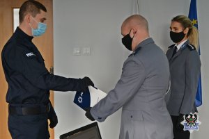 I Zastępca Komendanta Miejskiego Policji w Wałbrzychu podinsp. Rafał Siczek wręcza akt ślubowania jednemu z policjantów.