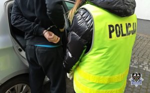 Na zdjęciu policjantka umieszcza zatrzymanego mężczyznę w radiowozie.