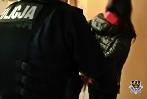 Na zdjęciu policjant zakłada kajdanki zatrzymanej kobiecie.