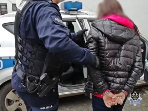 Na zdjęciu policjant umieszcza zatrzymaną kobietę w radiowozie.