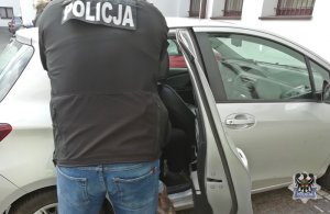 Na zdjęciu policjant umieszcza zatrzymanego mężczyznę w radiowozie.