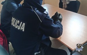 Na zdjęciu policjanci wykonują czynności procesowe z drugim z zatrzymanych mężczyzn - inne ujęcie.