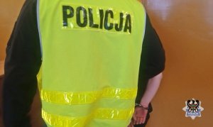 Na zdjęciu policjant prowadzi zatrzymanego mężczyznę.
