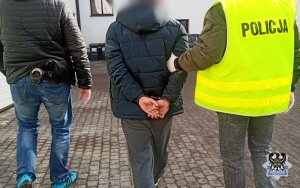 Na zdjęciu policjanci prowadzą pierwszego z zatrzymanych mężczyzn.