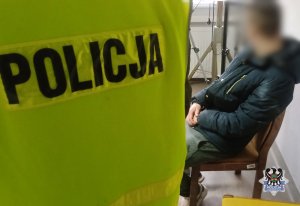 Na zdjęciu policjant pilnuje zatrzymanego mężczyznę.