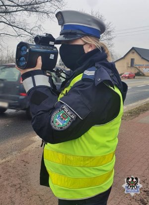 Na zdjęciu policjantka wykonująca ręczny pomiar prędkości - inne ujęcie.