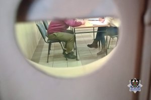 Na zdjęciu policjantka prowadzi czynności procesowe z jednym z zatrzymanych mężczyzn.