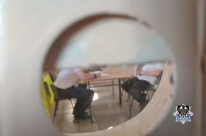 Na zdjęciu policjant wykonuje czynności procesowe z zatrzymanym mężczyzną.