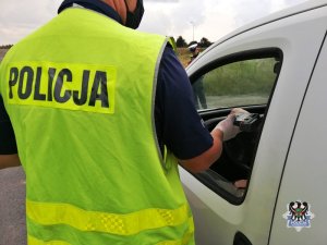 Na zdjęciu policjant wykonuje badanie na zawartość alkoholu w organizmie.