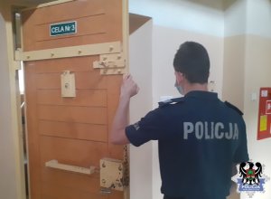 Policjant otwiera drzwi do celi